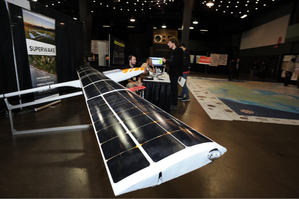 A large solar-panelled fixed-wing uncrewed aircraft displayed on the giant floor map of Canada