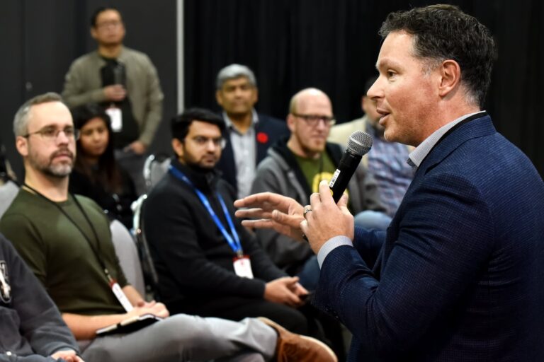 A speaker addresses a closely seated group with a handheld microphone
