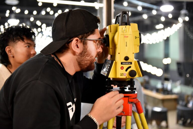 A student sights through the eyepiece of a total station during a hands-on surveying activity