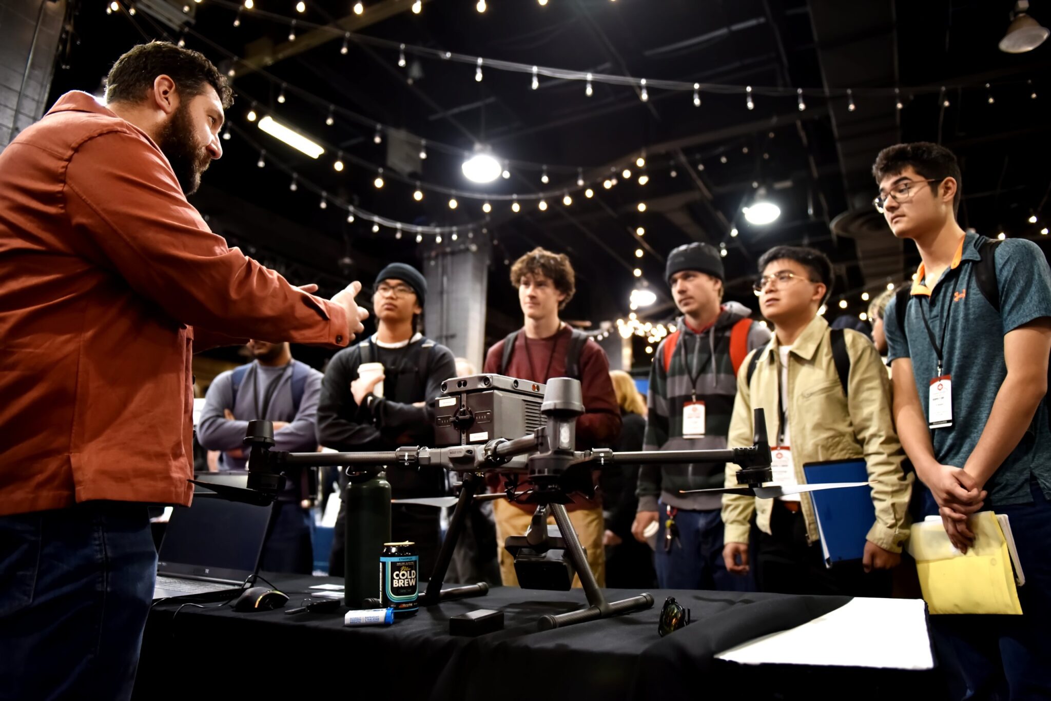 An exhibitor demonstrates a large multirotor drone to a group of delegates and students on the GoGeomatics Expo trade show floor