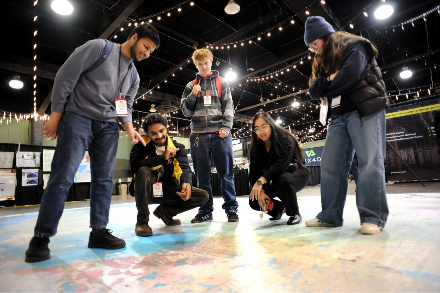 Students crouch and point at the giant floor map of Canada on the trade show floor